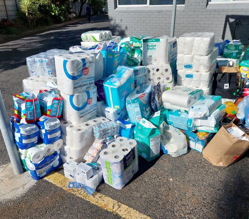 A large pile of donated goods, including blankets, toiletries, and non-perishable food, collected by The Wild Buggers Beach Buggy Club for Huis Uitsig seniors home.
