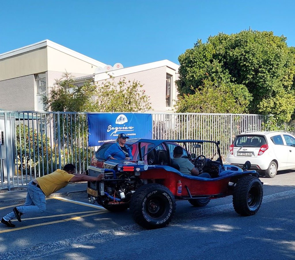 Members of The Wild Buggers Beach Buggy Club pushing a beach buggy at the Huis Uitsig charity event.