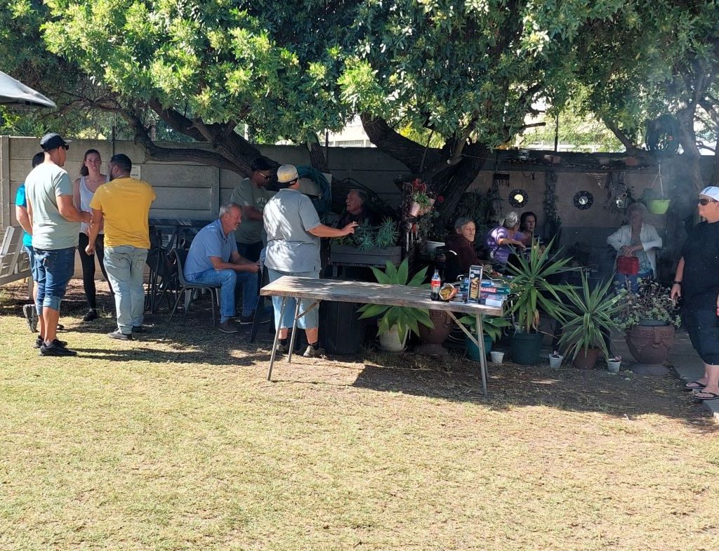 Wild Buggers Beach Buggy Club members sitting and chatting with senior residents at Huis Uitsig.