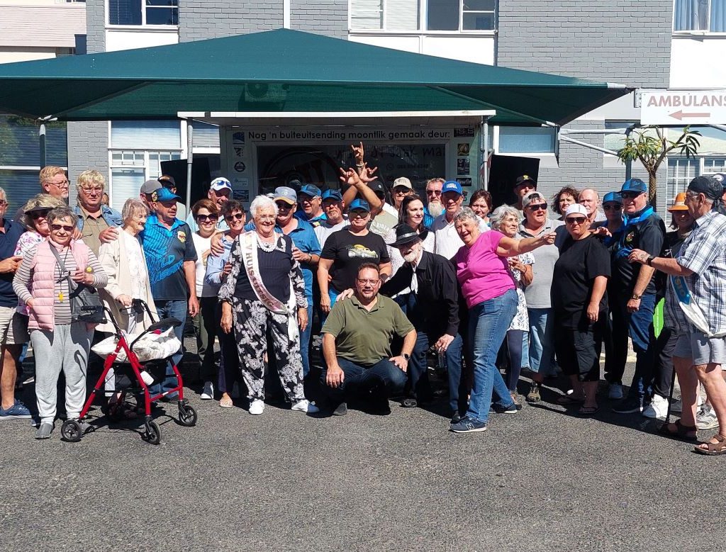 Group photo of The Wild Buggers Beach Buggy Club members and senior residents during the Huis Uitsig charity visit.