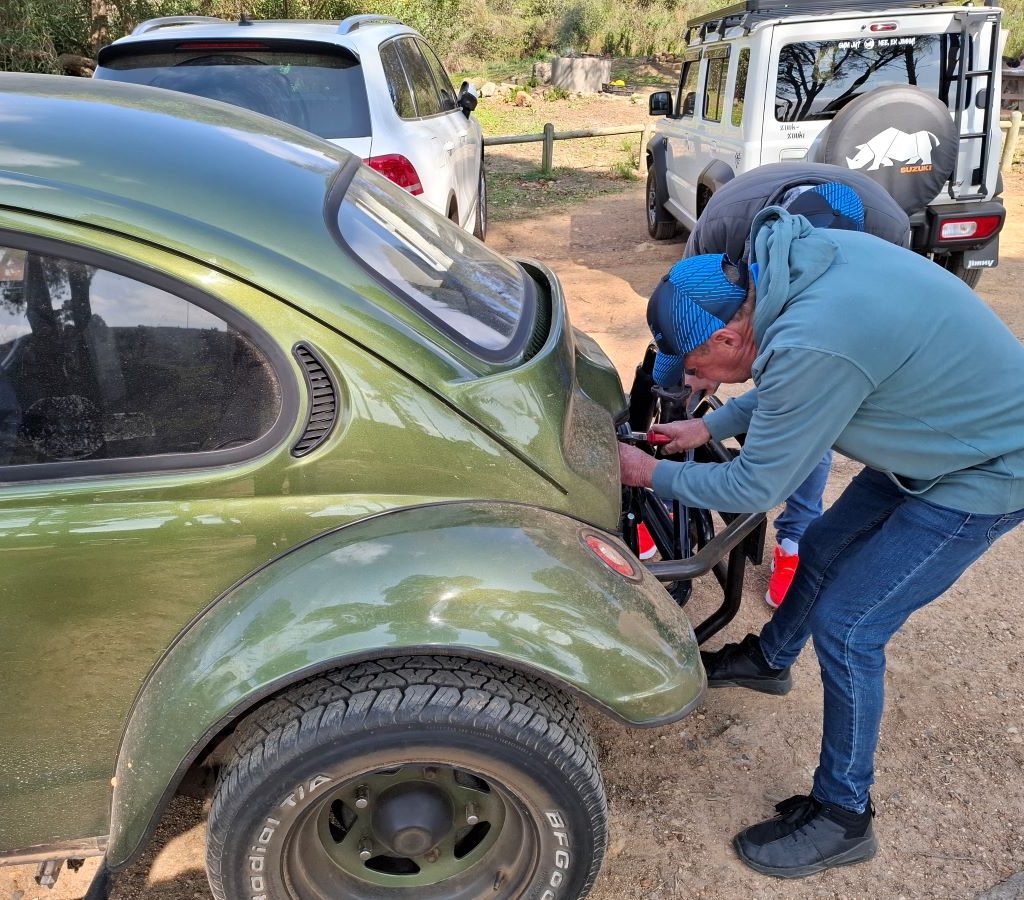Jessie setting the choke on Mickey's green Baja Bug, Dark Side, during a Wild Buggers Beach Buggy Club event.