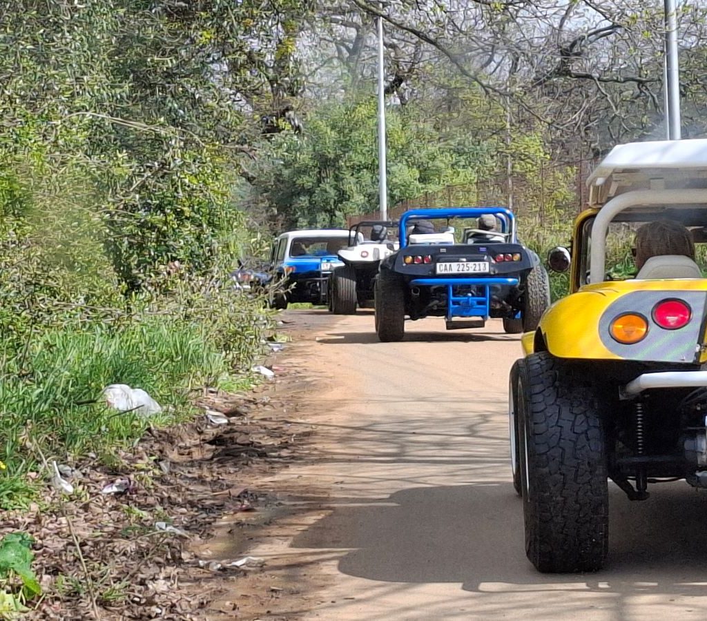 A different angle showing a line of Wild Buggers beach buggies driving up the mountain on a gravel road in Paarl.