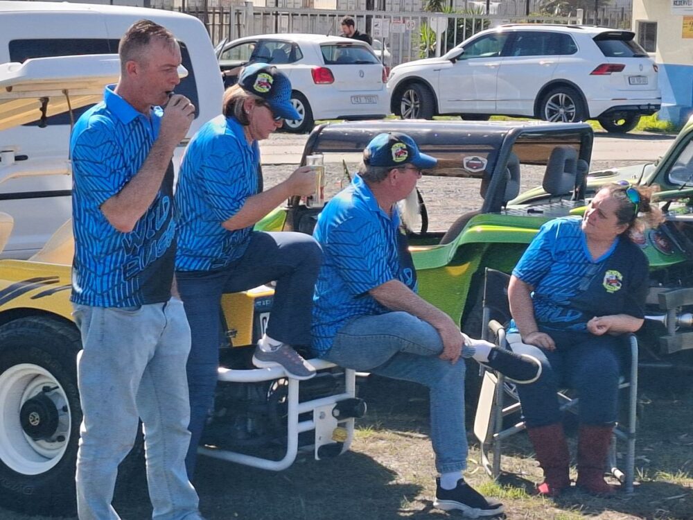 Wild Buggers Beach Buggy Club members chatting, showing off their vibrant club t-shirts and caps.