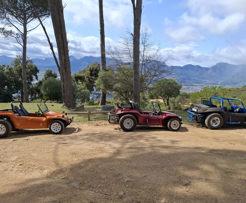 Landria’s orange Kasupi, Solandra’s red Bad Boy, and Clive & Linda’s beach buggy with the custom oil catcher, parked together at a Wild Buggers event.