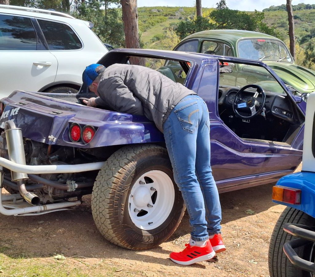 Mario Navarra, wearing his bright tekkies, looking for his toolbox in the back of Erica's purple Kango beach buggy.