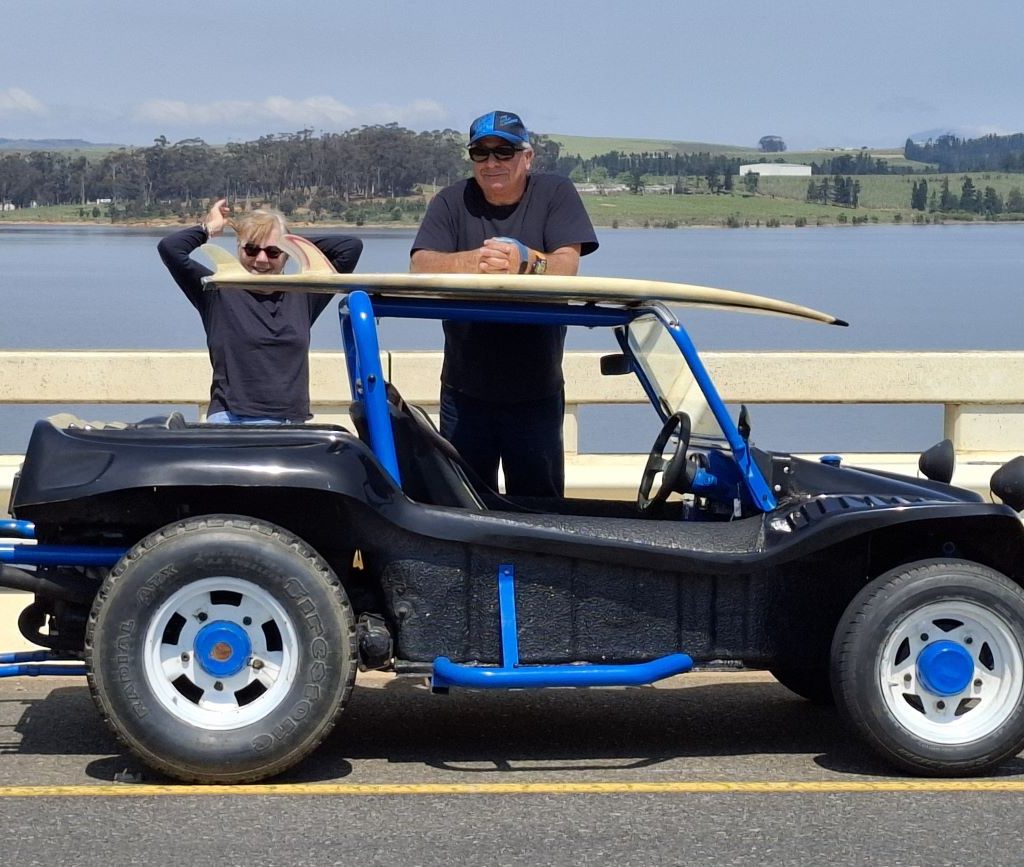 Clive and Linda standing by their black and blue beach buggy with the dam in the background during the Wild Buggers Winelands Breakfast Run.