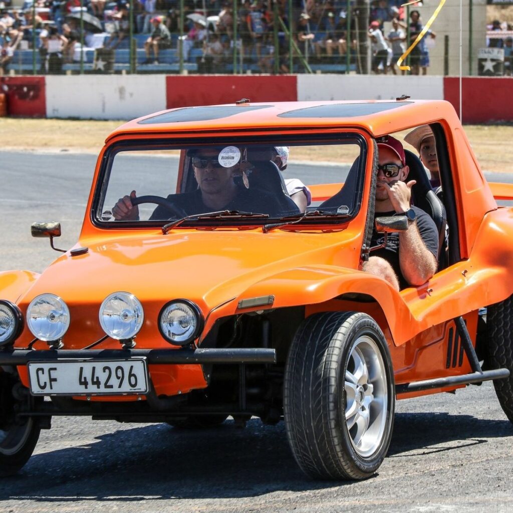 Brent driving his orange Salamander beach buggy with a VW air-cooled motor, carrying children around the track at the Wild Buggers Beach Buggy Club's Killarney International Raceway charity run.