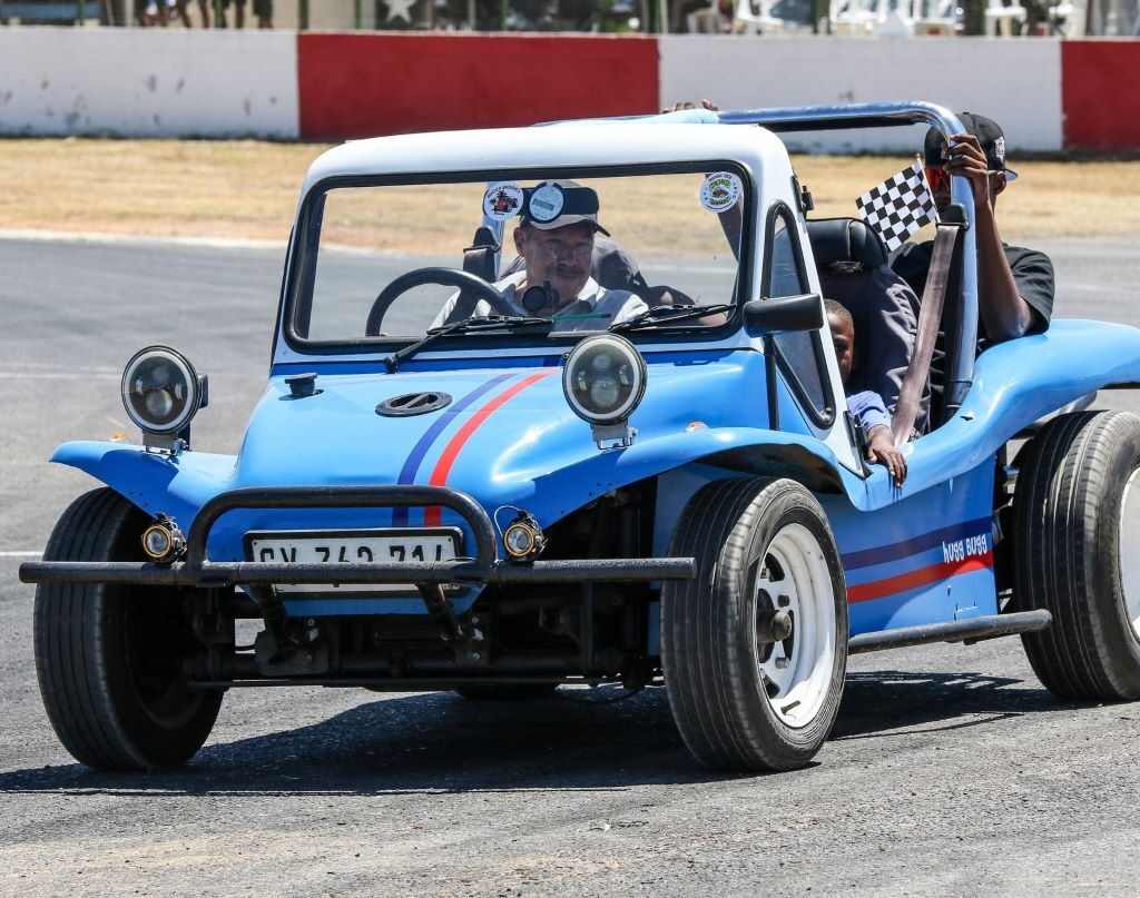 Jessie Huggett driving his blue Kestrel KartKraft beach buggy with a VW air-cooled Beetle motor, carrying children around the track at the Wild Buggers Beach Buggy Club's Killarney International Raceway charity run.