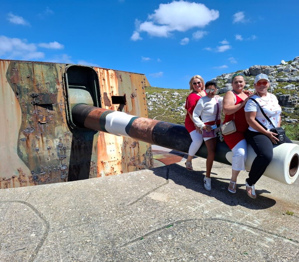 Michelle, Mickey, Ayesha, and Sam sitting on the barrel of The Cannon in Simon's Town during the Wild Buggers Beach Buggy Club's Valentine's Day run.