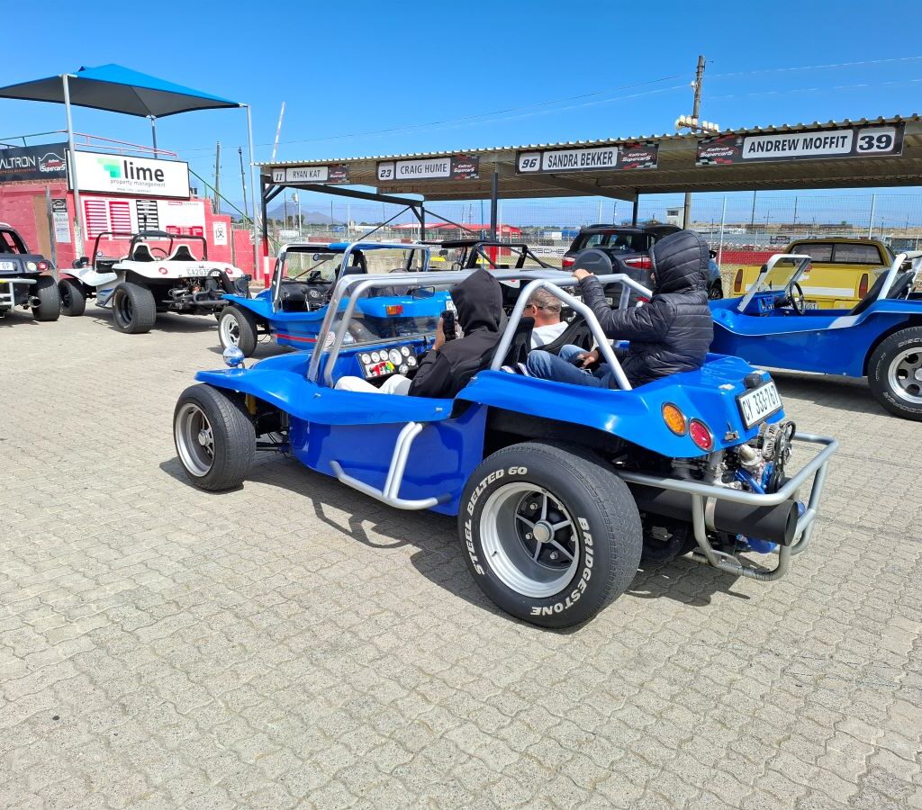 A photo showing Wild Buggers beach buggies and happy Reach for a Dream children at the Killarney International Raceway track, ready for another ride.