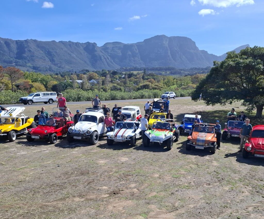 Beach buggies parked at a watering hole during the Cape Buggy Tour 2025, with members snapping photos and enjoying the stop.