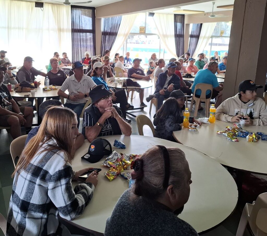 A photo inside the hall at the Reach for a Dream event, showing Wild Buggers members and parents of the children, all focused on the gift-giving and speeches.