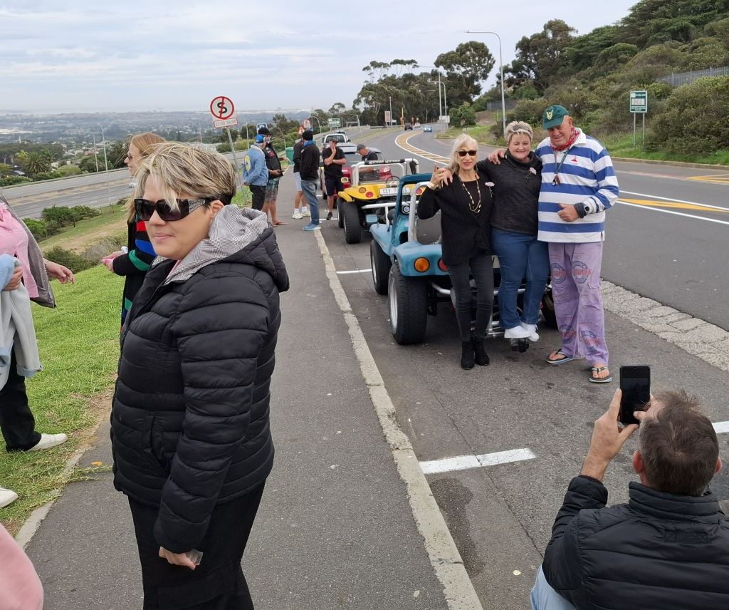 A line of diverse classic beach buggies and air-cooled VWs, gathered at the Uys Krige Lookout point, with Table Mountain or a scenic Cape Town backdrop, ready for Wiehann's Run.