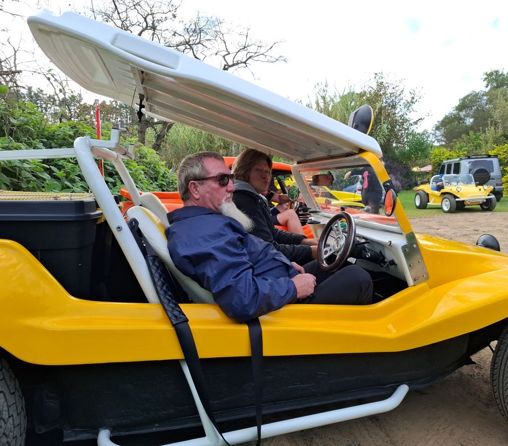 Chris and Sandra are pictured inside their beach buggy at Helderberg Farm, the milkshake stop on Wiehann's Run, preparing to exit the vehicle with smiles and anticipation.