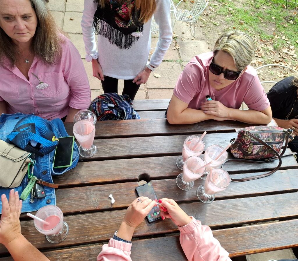 A group of Wild Buggers Beach Buggy Club members, all wearing black as a tribute, are enthusiastically receiving and enjoying their strawberry milkshakes at Helderberg Farm during Wiehann's Run.
