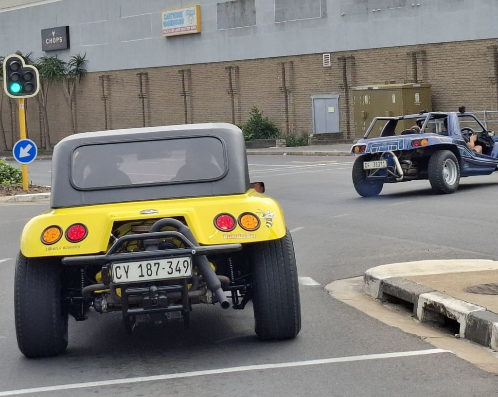 A vibrant yellow and a blue beach buggy, driven by Anthony and Lerene respectively, are seen making a right turn at a traffic light, during a Wild Buggers event.