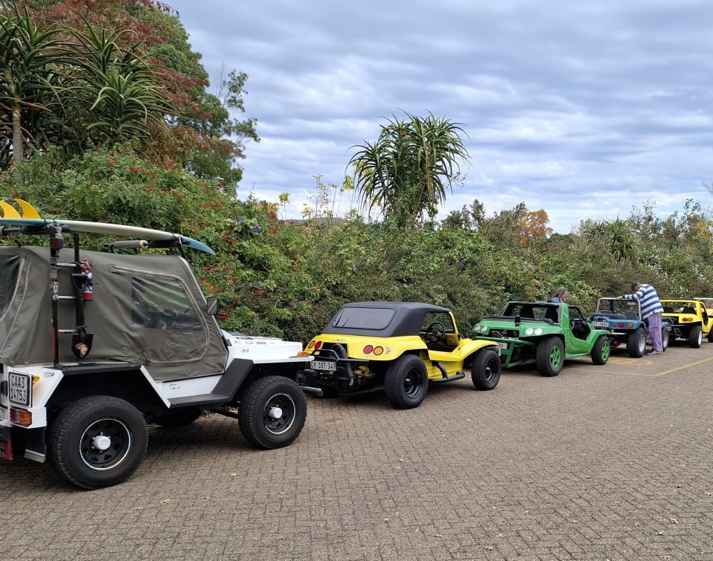 A group of Wild Buggers beach buggies parked together in a designated area at Lourensford Estate, indicating special parking arrangements, with the scenic garden in the background.