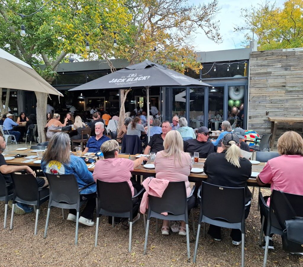 A very long table, set up for a large group, extends through a dining area at Lourensford Estate, indicating special arrangements made for the Wild Buggers Beach Buggy Club's lunch gathering.