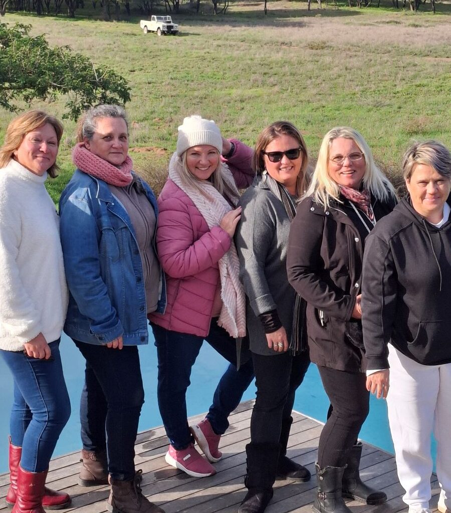 The ladies of The Wild Buggers Beach Buggy Club posing at the swimming pool, with a Land Rover visible in the background, during Tony & Sue's Run.