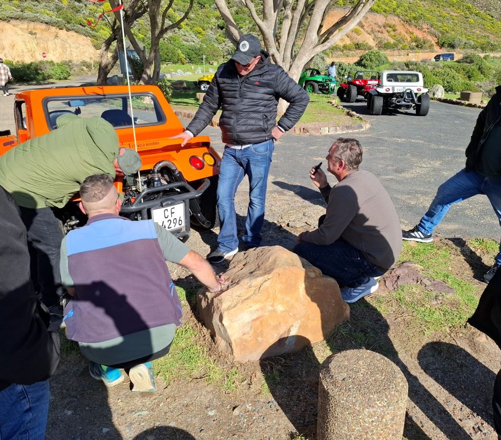 Wild Buggers gathered around Anthony as he works on Brent's beach buggy carburetor