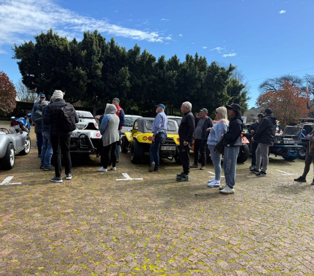 A photo of several Wild Buggers' club members gathered in the brewery's parking lot, chatting and socializing next to their vehicles before heading inside.