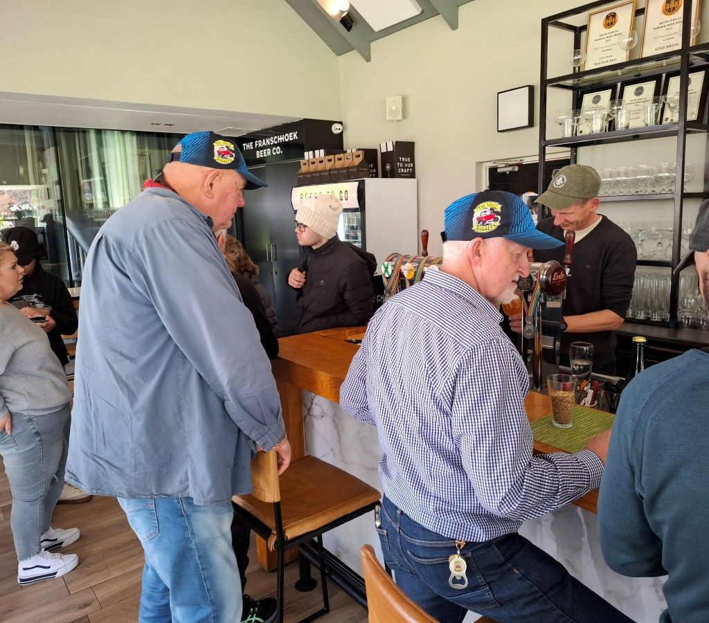 A photo of several Wild Buggers' club members standing at a bar, looking at the menu and still deciding on their drink orders after a long drive.