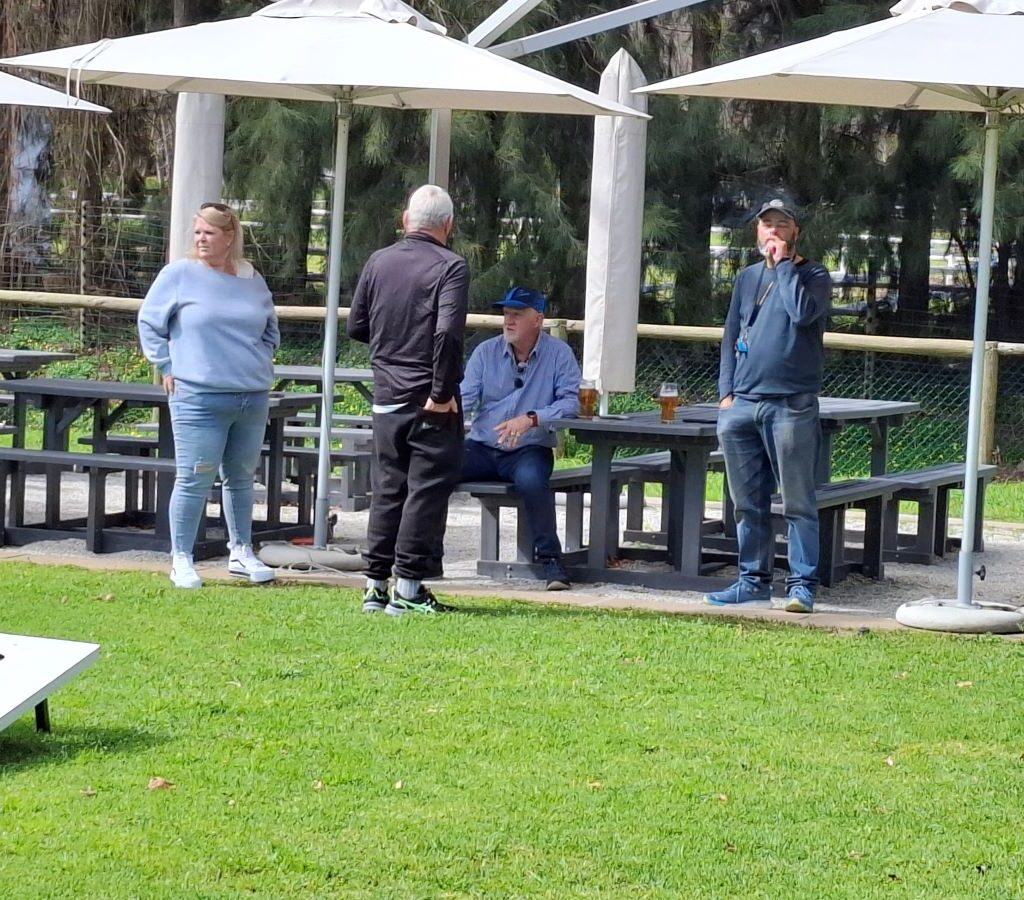 A photo of several Wild Buggers' club members sitting together outside the brewery, relaxing and socializing in the sun after their drive.