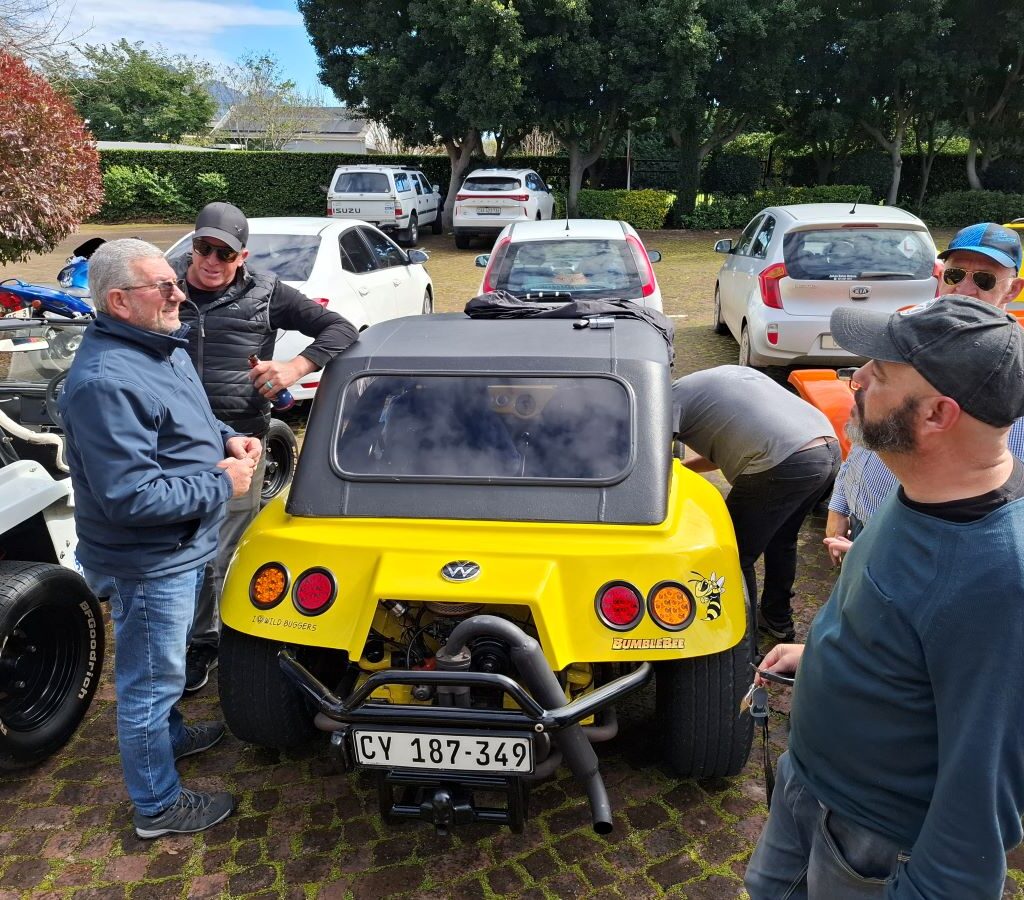 A photo of several Wild Buggers' club members gathered in the brewery's parking lot, preparing to leave and get back on the road in their vehicles.
