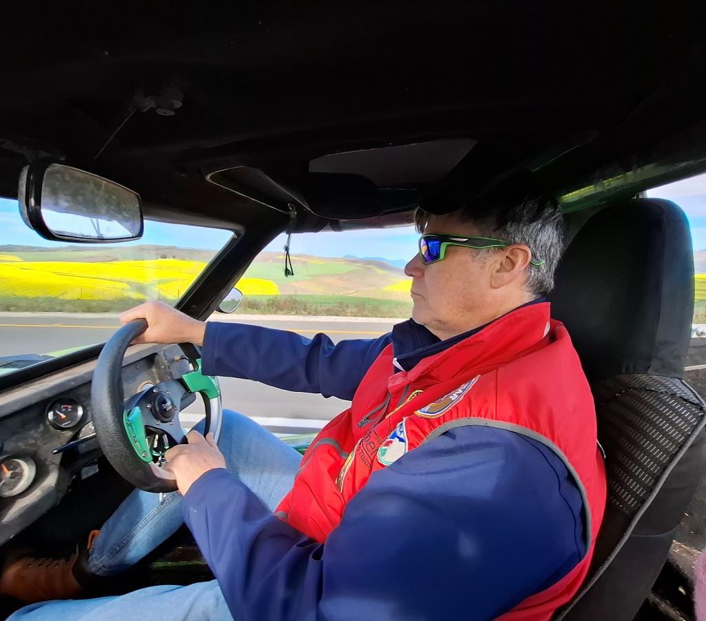 A photo of Anton Kleyn, the President of the Wild Buggers Beach Buggy Club, in the driver's seat of his vehicle, smiling and enjoying the drive on a club run.