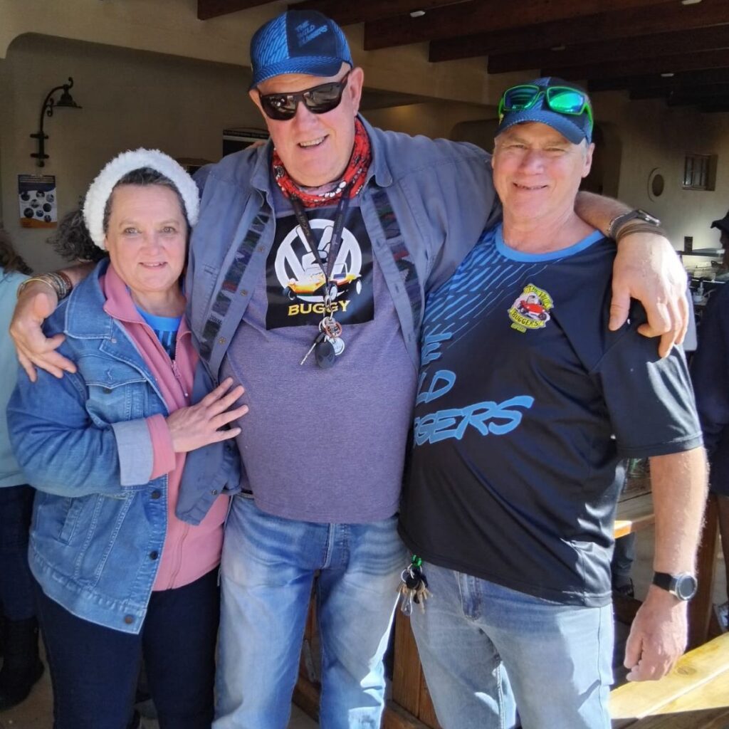 A photo of three Wild Buggers' club members: Geno, Mickey, and Anton Kleyn, the club president, smiling together during a break on their run.