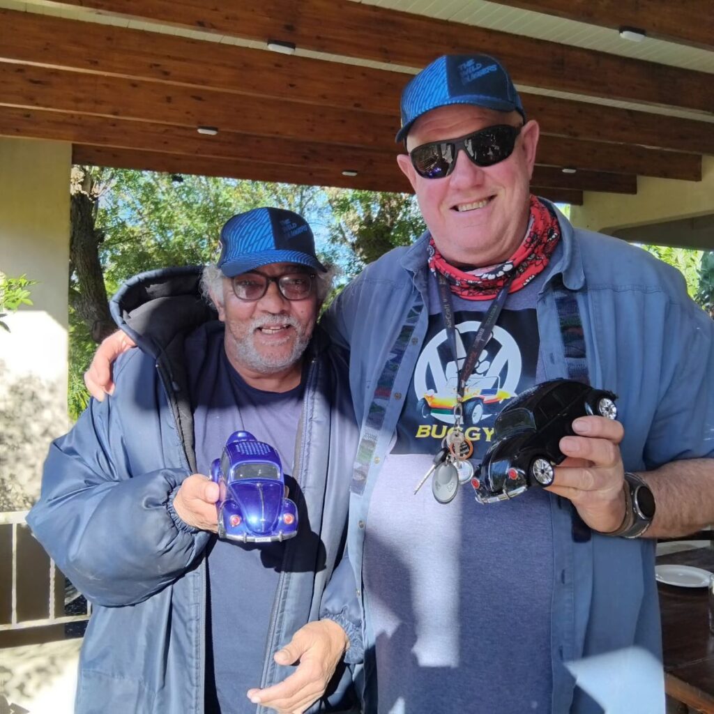 A photo of two Wild Buggers' club members, Fabian and Geno, smiling and holding their unique Bluetooth radios shaped like classic VW Beetles.