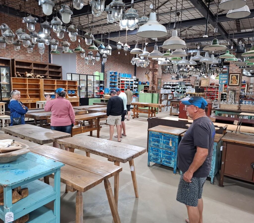 A casual photo inside the Kooperasie Stories antique store, showing a general view of the eclectic display of vintage furniture, collectibles, and rustic items, captured during the Wild Buggers club drive pitstop.