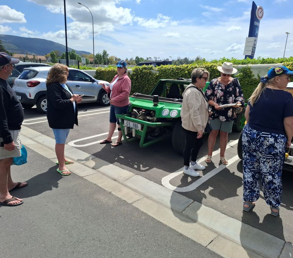 A candid photo taken in the Paarl shopping centre parking lot showing several Wild Buggers members gathered and chatting next to their parked beach buggies and VW air-cooled vehicles while waiting for the rest of the club to finish shopping.