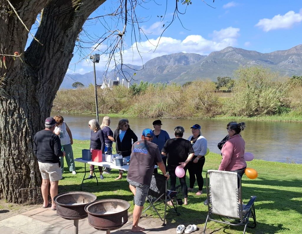 A comical and engaging photo of the Wild Buggers "Ladybugs" (Sandra, Sam, Michelle, Mickey, Yolande, and Linda) at the Bergriver Resort camp, laughing while wearing balloons tied around their waists and positioned comically behind their backs. The image captures a spontaneous moment of pure, silly fun.