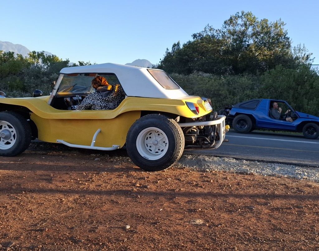 A photo taken at the Taal Monument in Paarl during an evening drive, showing Rhoodie's blue beach buggy and Jacques's yellow beach buggy executing a turn-around maneuver after finding the monument gates closed.