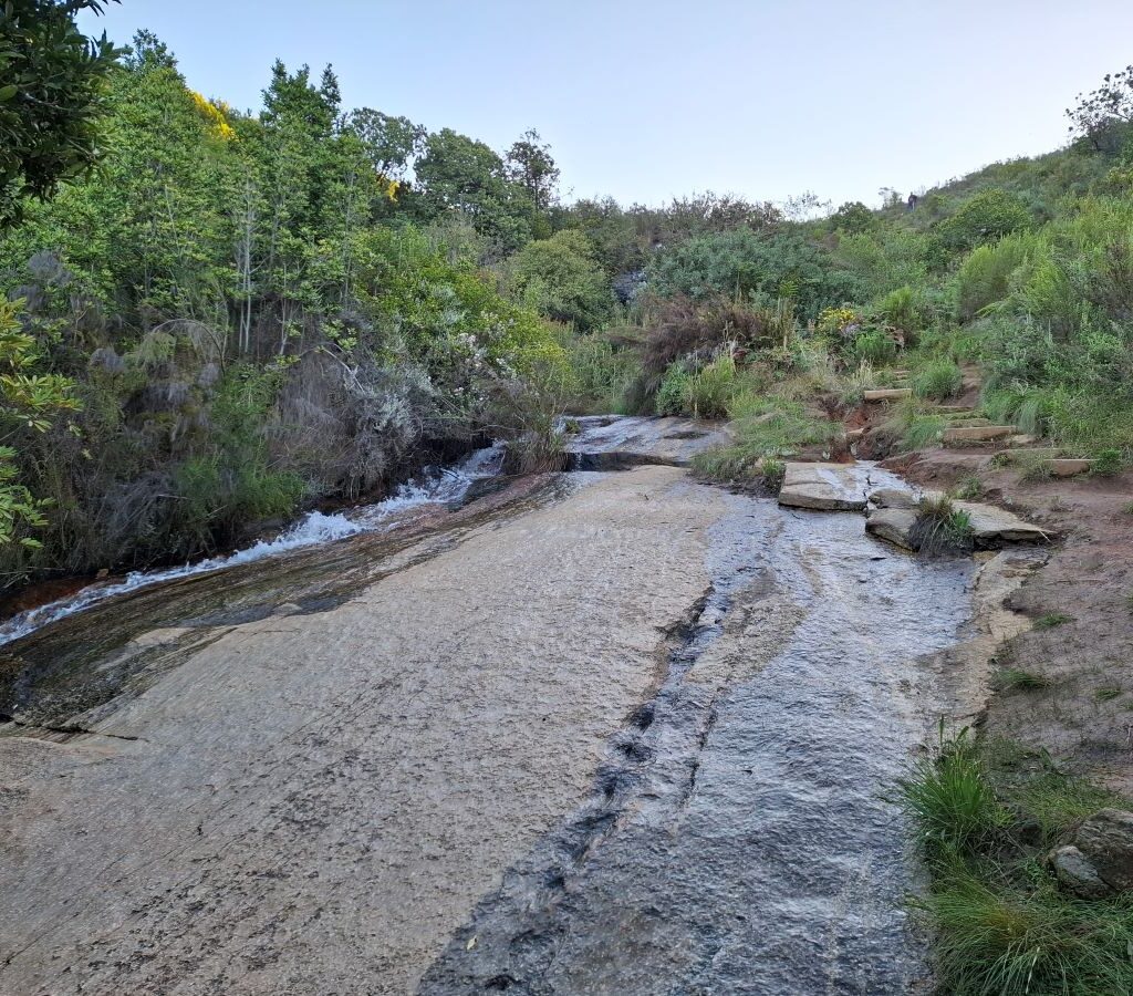A beautiful, descriptive photo of a waterfall cascading over rocks, captured during a spontaneous stop on the Wild Buggers club drive, highlighting the natural beauty found on the scenic route.