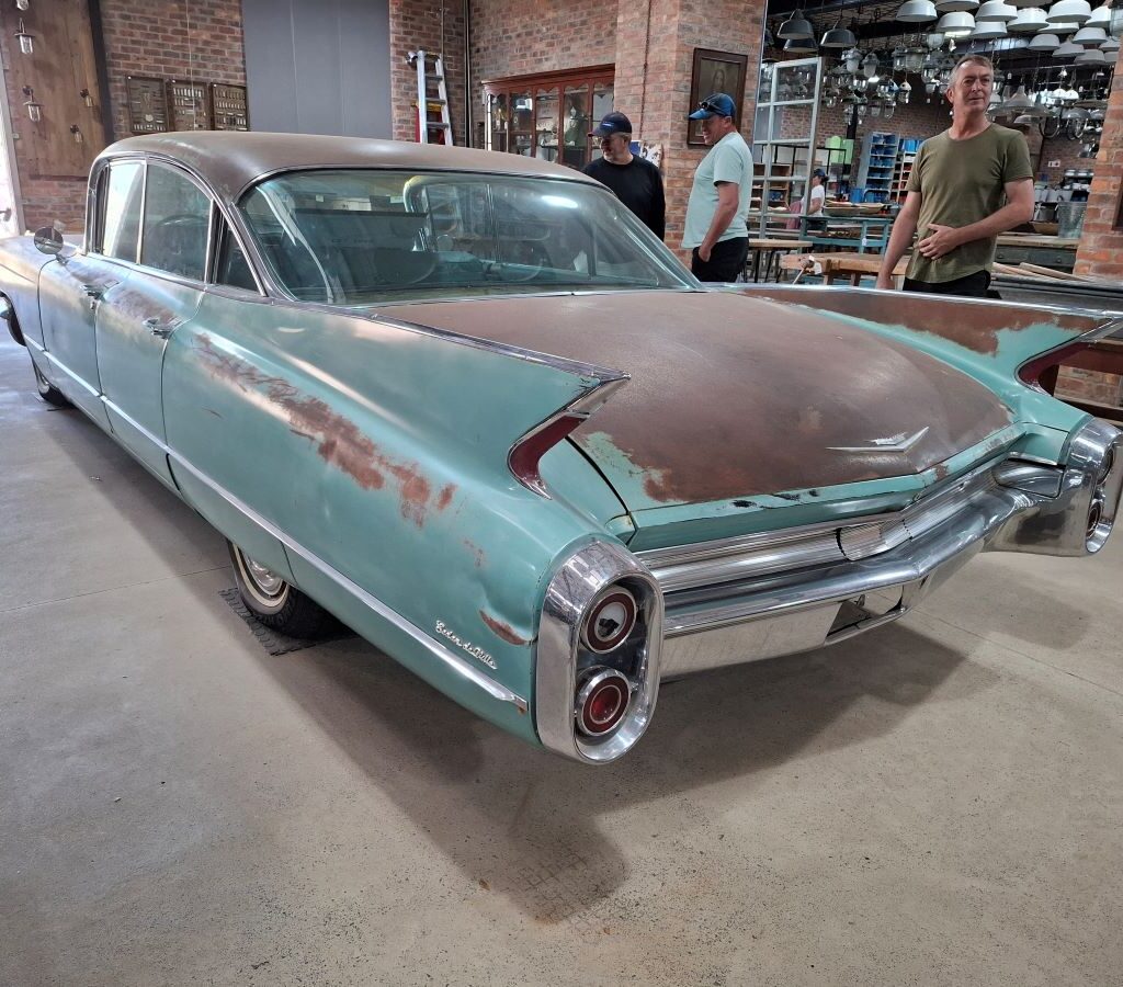 A humorous photo taken during the Wild Buggers morning drive pitstop at Kooperasie Stories in Simondium. The image shows a very large, antique, classic car on display inside the store.