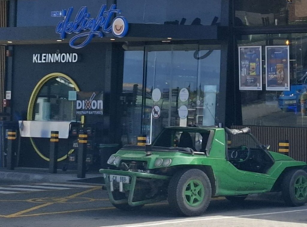 The green Kango Beach Buggy, "Shrek," is pictured parked at a garage in Kleinmond during a Wild Buggers road trip.