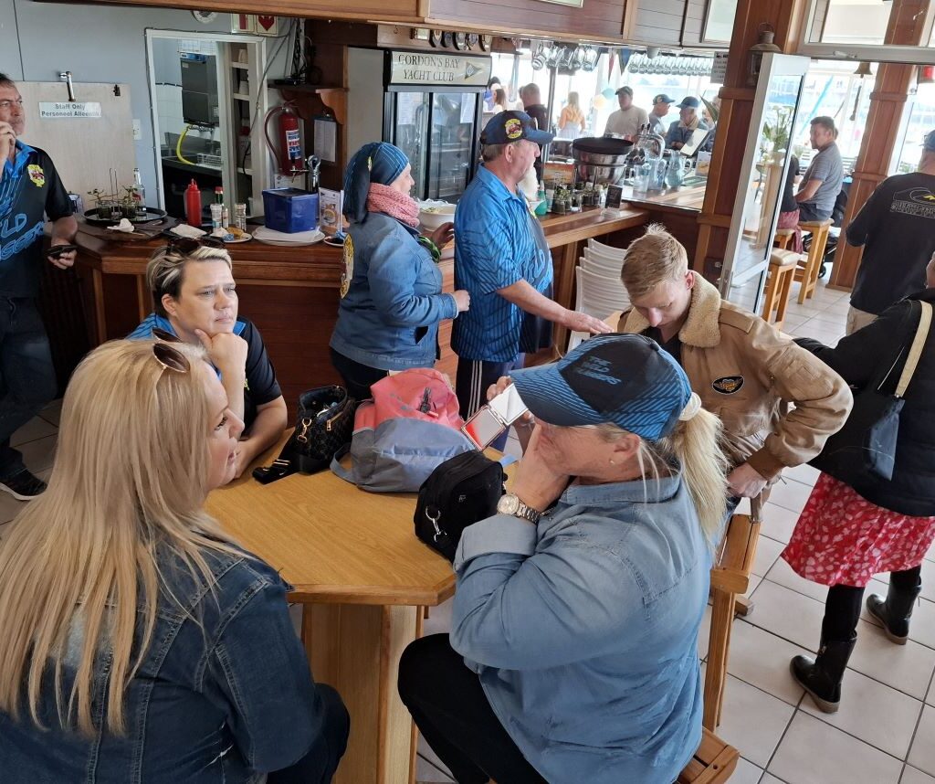 Members of the Wild Buggers club are inside the Gordon's Bay Yacht Club, ordering drinks at the bar after their road trip.