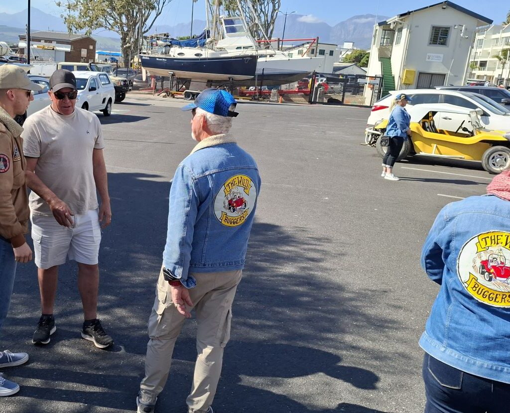 Brent, Kyle, and Jacques are pictured having a final chat in a parking area as other Wild Buggers members wait by their VW Air cooled vehicles.