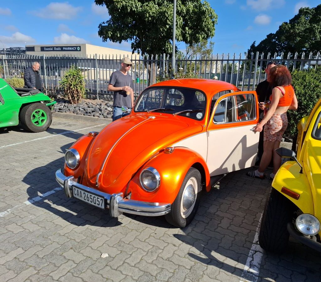 A potential new member, Chuckey, sits proudly in his orange VW air-cooled Beetle at a Wild Buggers club event.