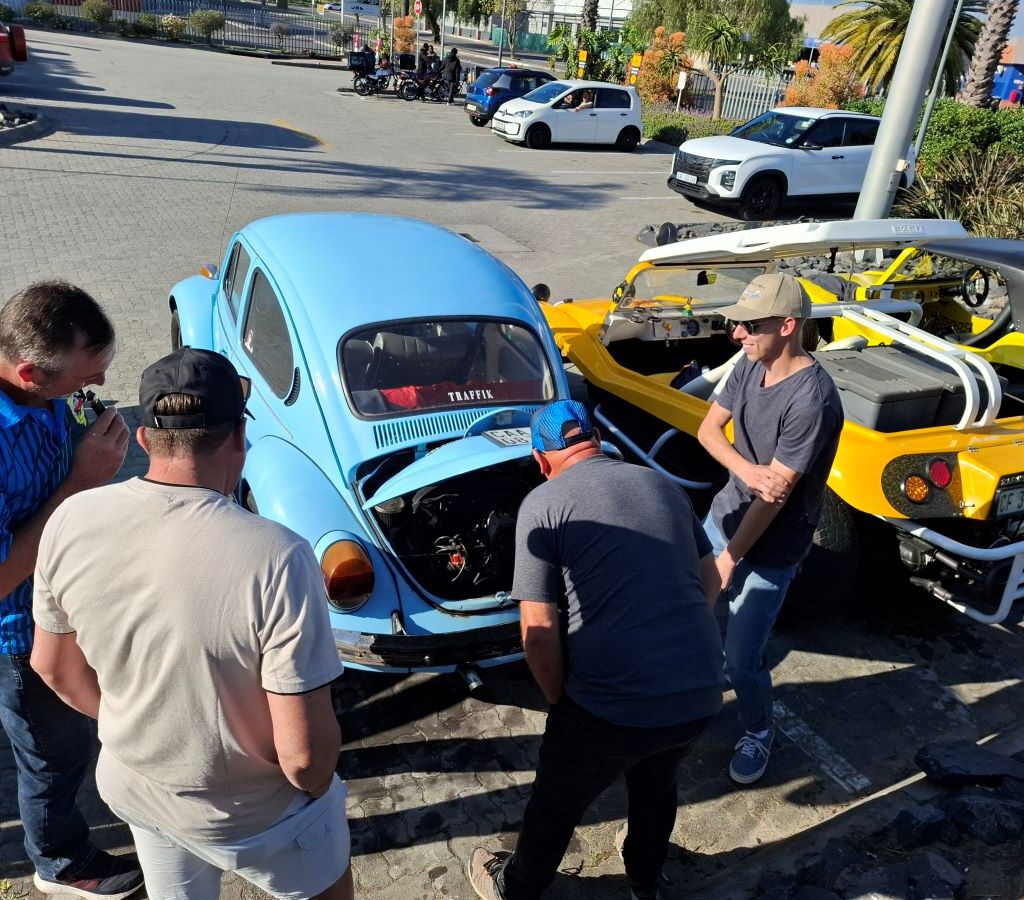 Kyle shows off the engine of his blue VW Air-cooled Beetle to a group of fellow Wild Buggers at the event meeting point.