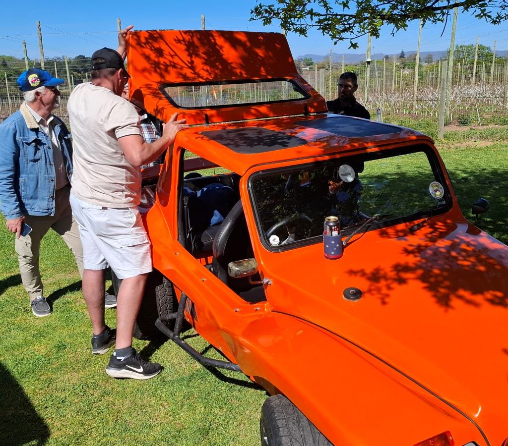 Brent demonstrates how the canopy works on his VW beach buggy, "The Wasp," to other Wild Buggers members at Peregrine Farm Stall.