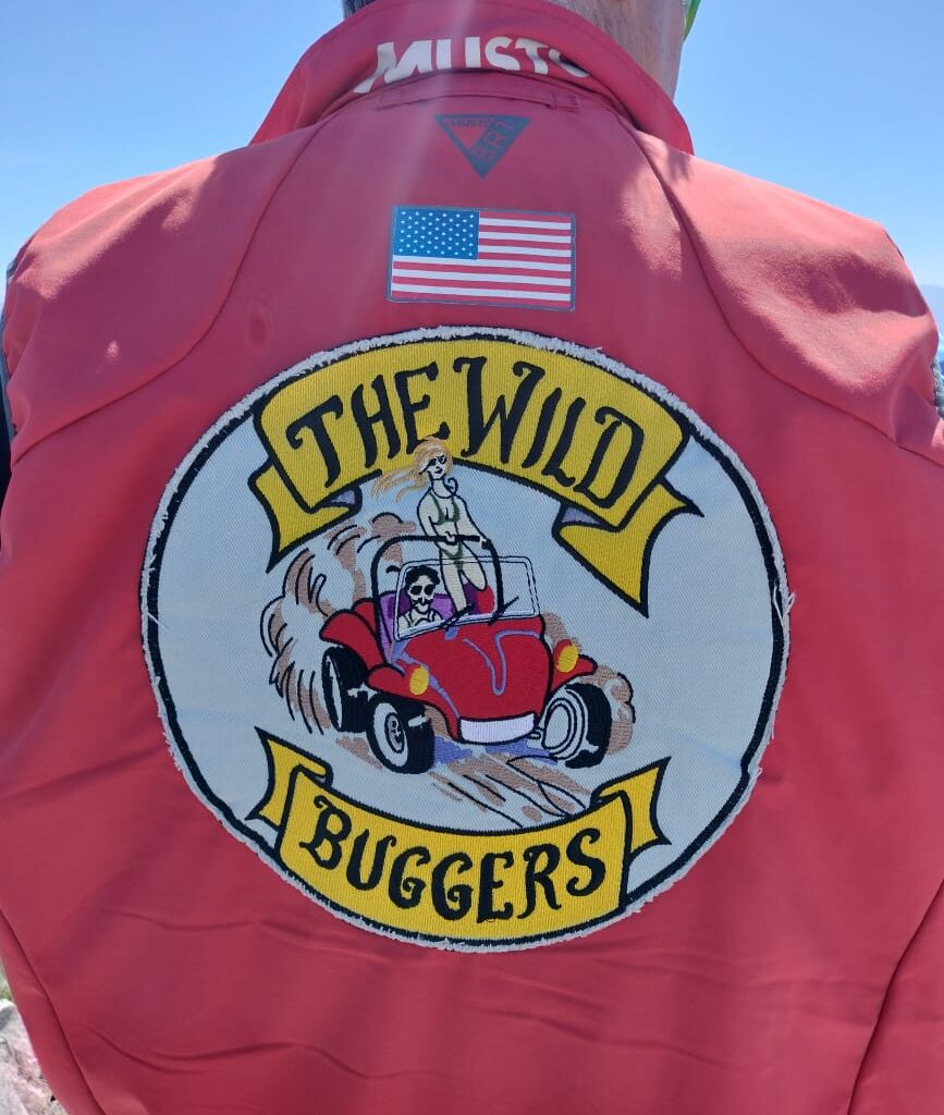 The back of a Wild Buggers club member's jacket, showing the club colors, is pictured as they stand on the edge of a cliff.
