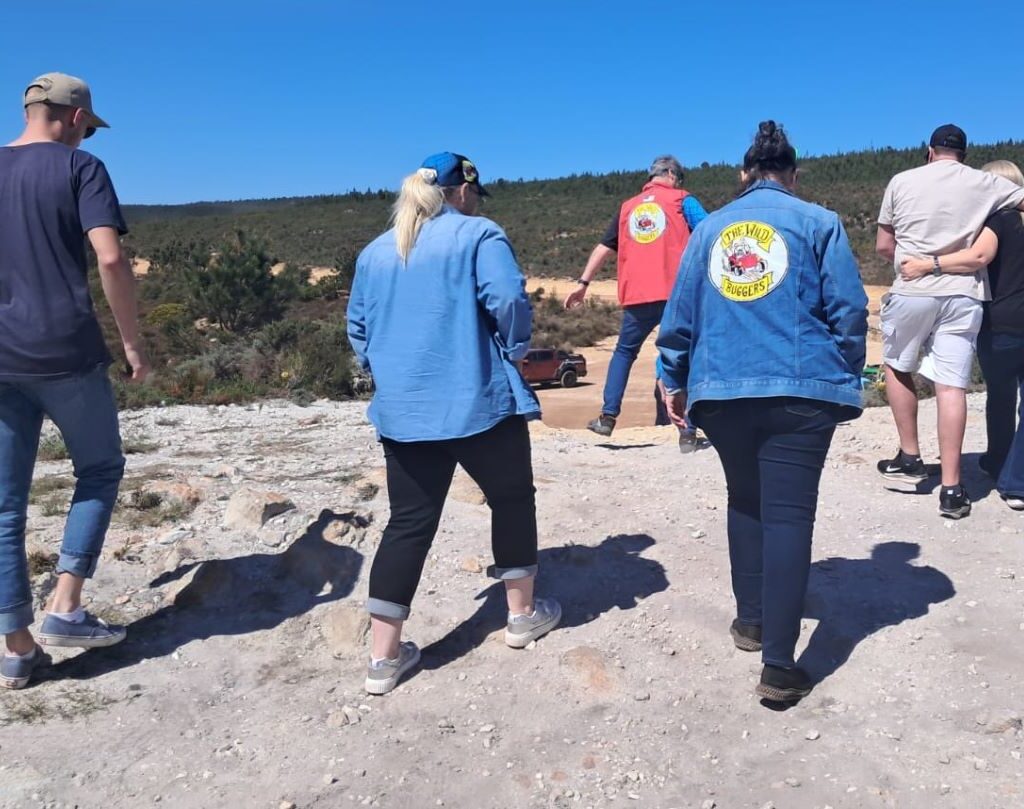 Members of the Wild Buggers club are walking away from a scenic lookout point to return to their VW Air cooled vehicles.