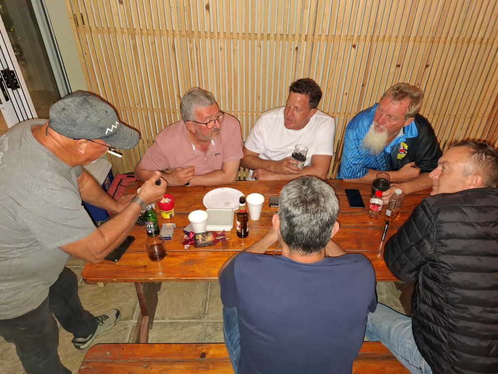 Wild Buggers members gathered around a table engaged in deep conversation at the Year-End Bash.