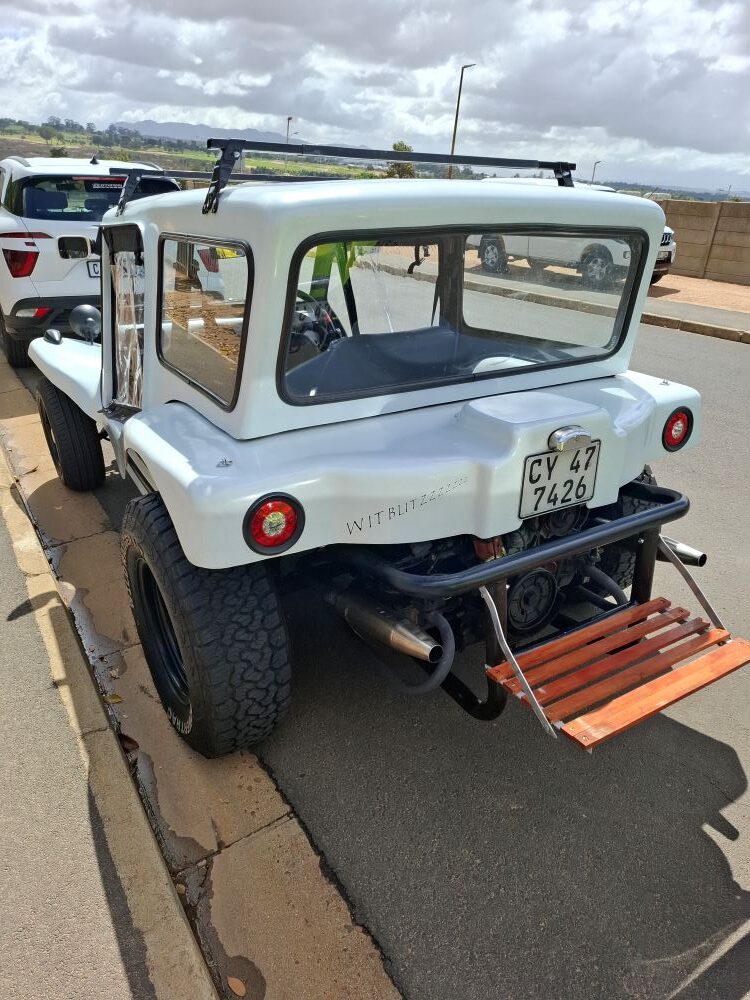 A custom white VW air-cooled Kestrel KartKraft beach buggy with a unique wooden rear luggage rack or seat.