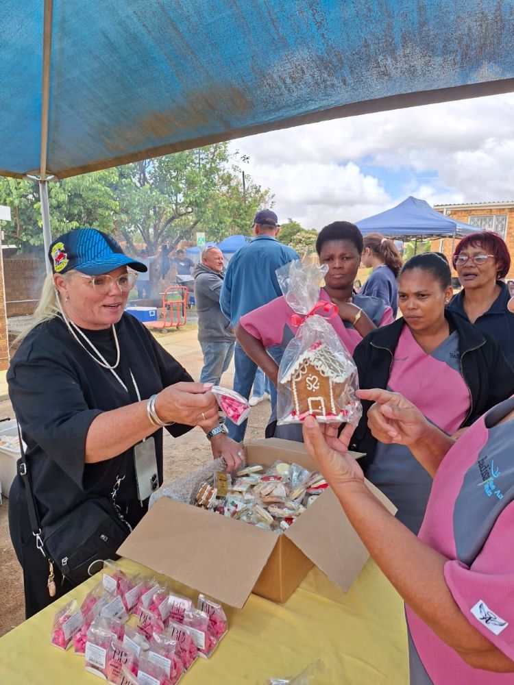 A Wild Buggers club member handing out decorated gingerbread house biscuits and gift packs to the nursing staff at the Goue Aar home.