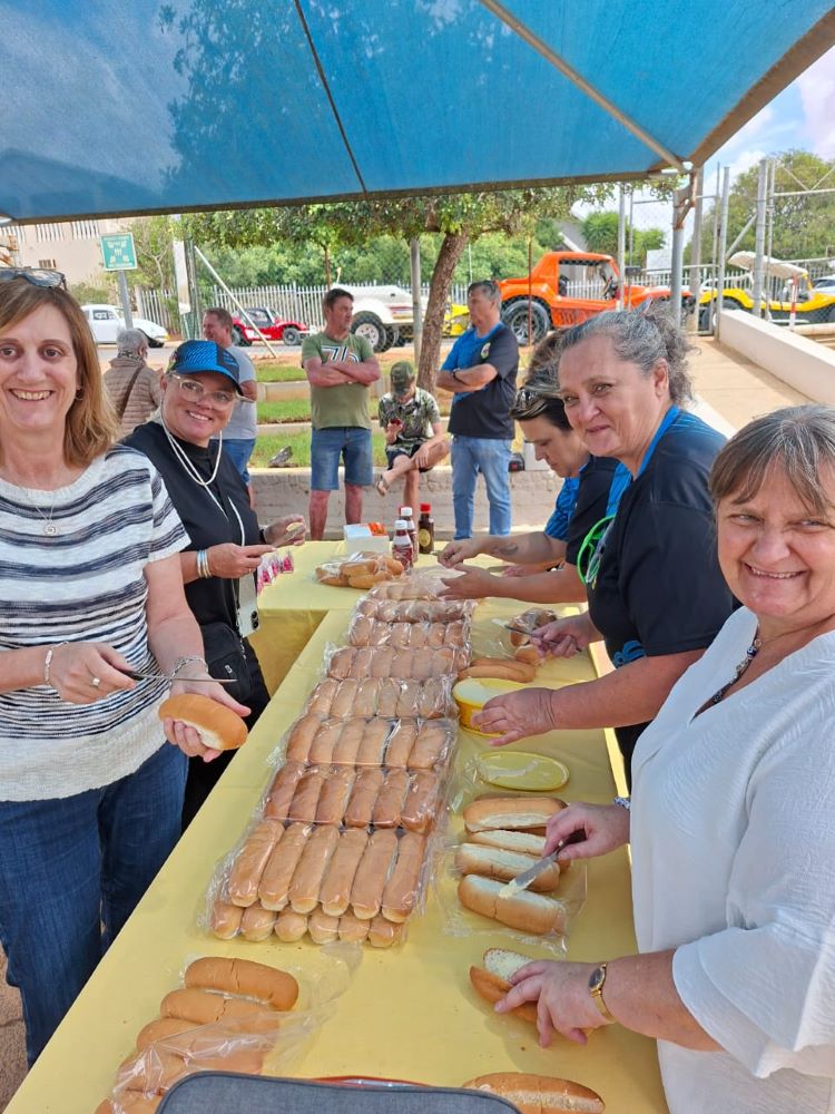 The Wild Buggers "Ladybugs" smiling while preparing rows of fresh rolls for the charity boerewors lunch at Goue Aar.