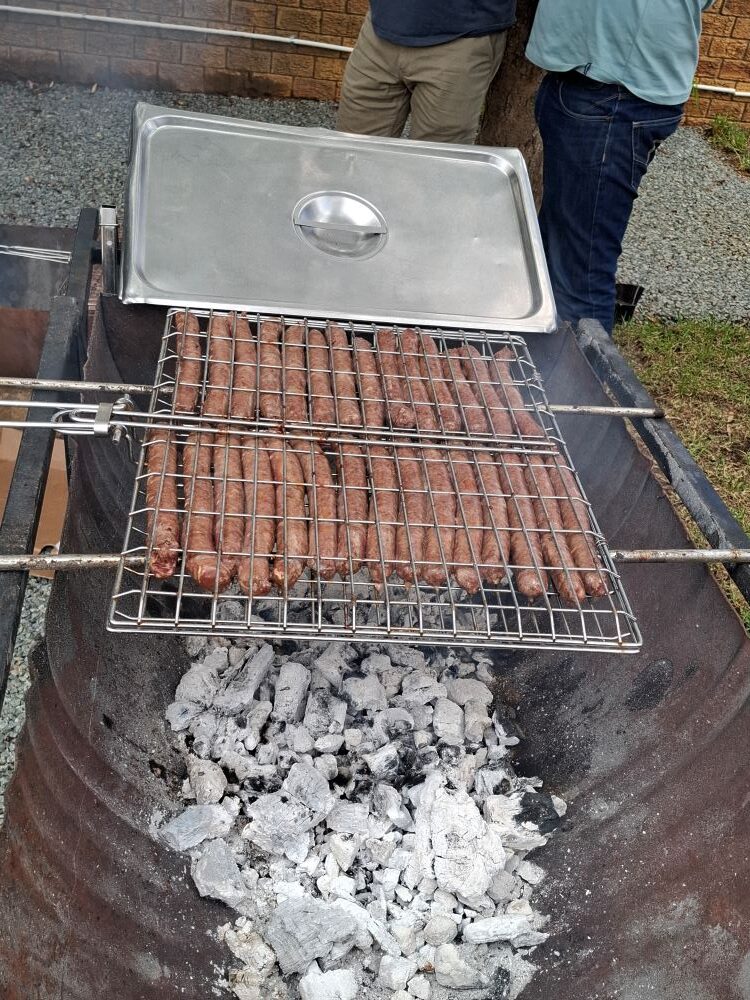Thick boerewors sizzling on a grid over hot coals during the Wild Buggers charity event braai at Goue Aar.